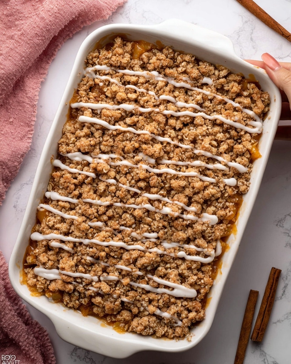 A close-up of a square piece of baked dessert being lifted by a black spatula, showing three visible layers: the bottom layer is soft and light beige, the middle layer is thick with chunks of orange and brown baked fruit, and the top layer is a crumbly oat streusel with a light drizzle of white icing. The dessert sits on a white plate on a white marbled texture surface, with a slightly blurred background including a woman’s hand holding the spatula. Photo taken with an iphone --ar 4:5 --v 7