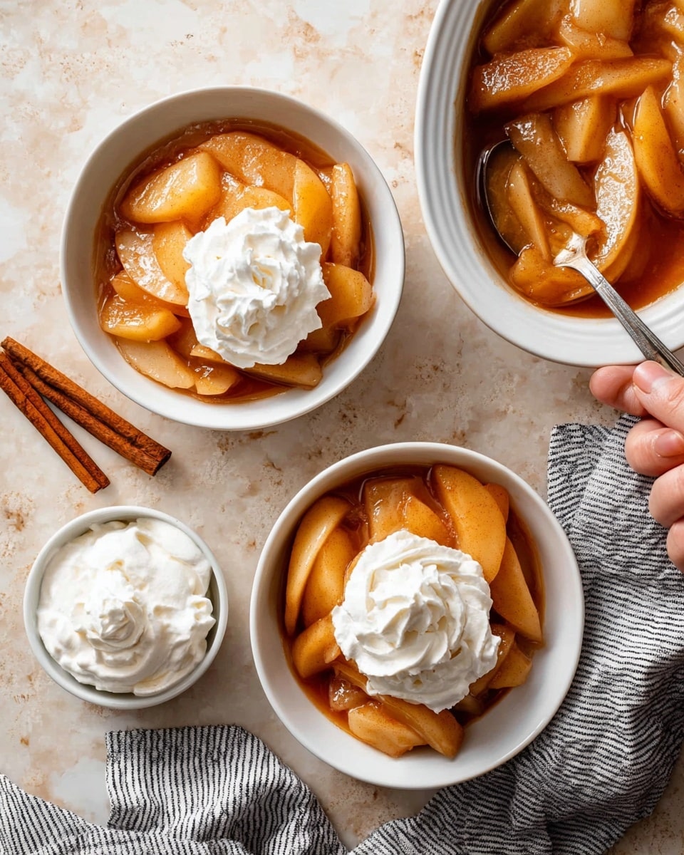 The image shows a white oval baking dish filled with thick slices of apple coated in a glossy, light brown sauce with visible cinnamon specks. The apple slices are layered in a slightly overlapping way, filling the dish almost to the top, with a wooden spoon resting on the right side inside the dish. The dish sits on a surface with a white marbled texture, and a gray striped cloth is placed nearby. photo taken with an iphone --ar 4:5 --v 7