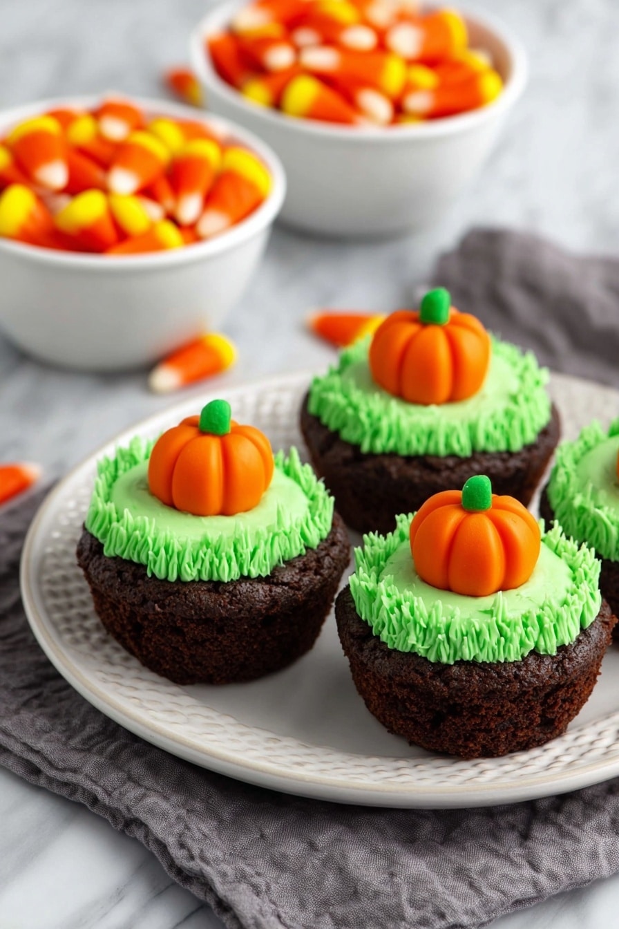 Pumpkin Patch Brownie Bites, mini autumn brownies, Halloween party treats, seasonal dessert ideas, festive brownie bites - The image shows a close-up of a rich, dark brown brownie cupcake on a white plate with a white marbled background. The cupcake has one layer of dense, moist chocolate cake with a slightly rough texture. On top is a thick swirl of bright green frosting, piped in tight loops to form a textured ring around the center. In the center of the frosting sits a small, smooth orange pumpkin-shaped candy with green leaves on top, adding a pop of color and detail. Photo taken with an iphone --ar 2:3 --v 7