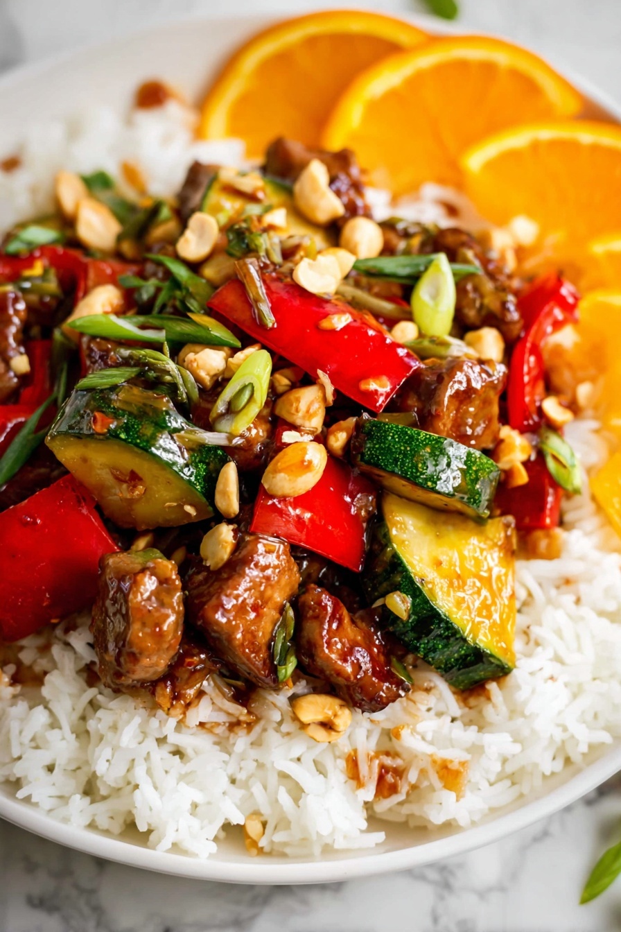 Kung Pao Chicken, Chinese stir-fry, spicy chicken recipe, easy weeknight dinner, Chinese takeout-inspired dishes - The dish is served on a white plate with a base layer of fluffy white rice spread evenly. On top of the rice, there is a colorful mix of stir-fried vegetables and meat pieces. The vegetables include vibrant red bell peppers and green zucchini chunks, both cut into bite-sized pieces with a glossy, cooked texture. Scattered throughout are small chunks of browned meat coated in a shiny, slightly sticky sauce. There are also whole light brown peanuts and thinly sliced green herbs sprinkled on top, adding some texture and color contrast. In the background, there are slices of bright orange fruit, adding a fresh, citrusy touch. The whole presentation sits on a white marbled surface. photo taken with an iphone --ar 2:3 --v 7