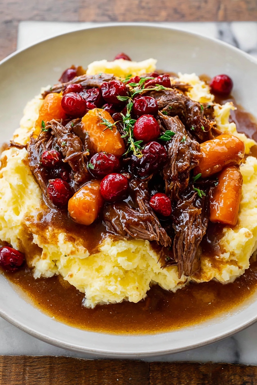 Cranberry Balsamic Roast Beef, roast beef with cranberries and balsamic, tender roast beef recipe, holiday roast beef ideas, flavorful beef dinner - A white plate holds a dish with three main layers: the base is a thick, creamy mashed potato layer, pale yellow and textured with soft peaks; on top of that sits a rich brown gravy mixed with tender, shredded dark brown beef pieces; the top layer features bright orange carrot slices and glossy red cranberries scattered throughout, with small green herb sprigs for garnish. The gravy looks shiny and slightly thick, pooling a little on the plate around the mashed potatoes. The whole plate is on a white marbled surface. photo taken with an iphone --ar 2:3 --v 7