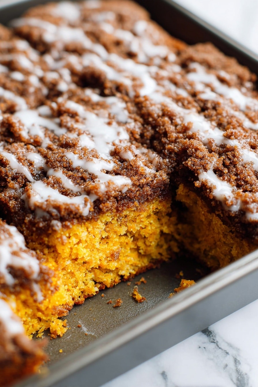 Pumpkin Coffee Cake with Streusel Topping, Autumn Pumpkin Coffee Cake, Fall Coffee Cake Recipes, Pumpkin Dessert with Streusel, Cozy Pumpkin Breakfast Cake - A close-up view of a square cake in a baking pan, showing one large piece missing from the corner of the cake. The cake has two visible layers: the bottom layer is bright orange with a moist and soft texture, and the top layer is thick with a dark brown crumbly topping mixed with a white glaze lightly drizzled over it. The baking pan is metallic, and the background surface is a white marbled texture. photo taken with an iphone --ar 2:3 --v 7
