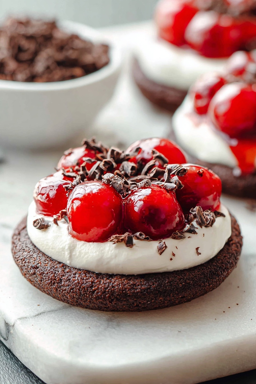 Chocolate Cherry Cheesecake Cookies, chocolate cherry cookies, cheesecake cookie recipe, cherry chocolate dessert, soft chewy cookies - The image shows a dessert with three layers on a white marbled surface. The bottom layer is a thick, round dark brown chocolate cookie with a coarse texture. The middle layer is a white creamy topping, spread evenly in a smooth circle covering the cookie’s surface. On top, there is a shiny bright red cherry topping that looks wet and glossy, with whole cherries visible. Small dark brown curled chocolate pieces are sprinkled over the cherry topping and creamy layer, adding texture and contrast. In the background, a white bowl filled with more dark brown chocolate curls is blurred, along with a second dessert of the same kind slightly out of focus. photo taken with an iphone --ar 2:3 --v 7