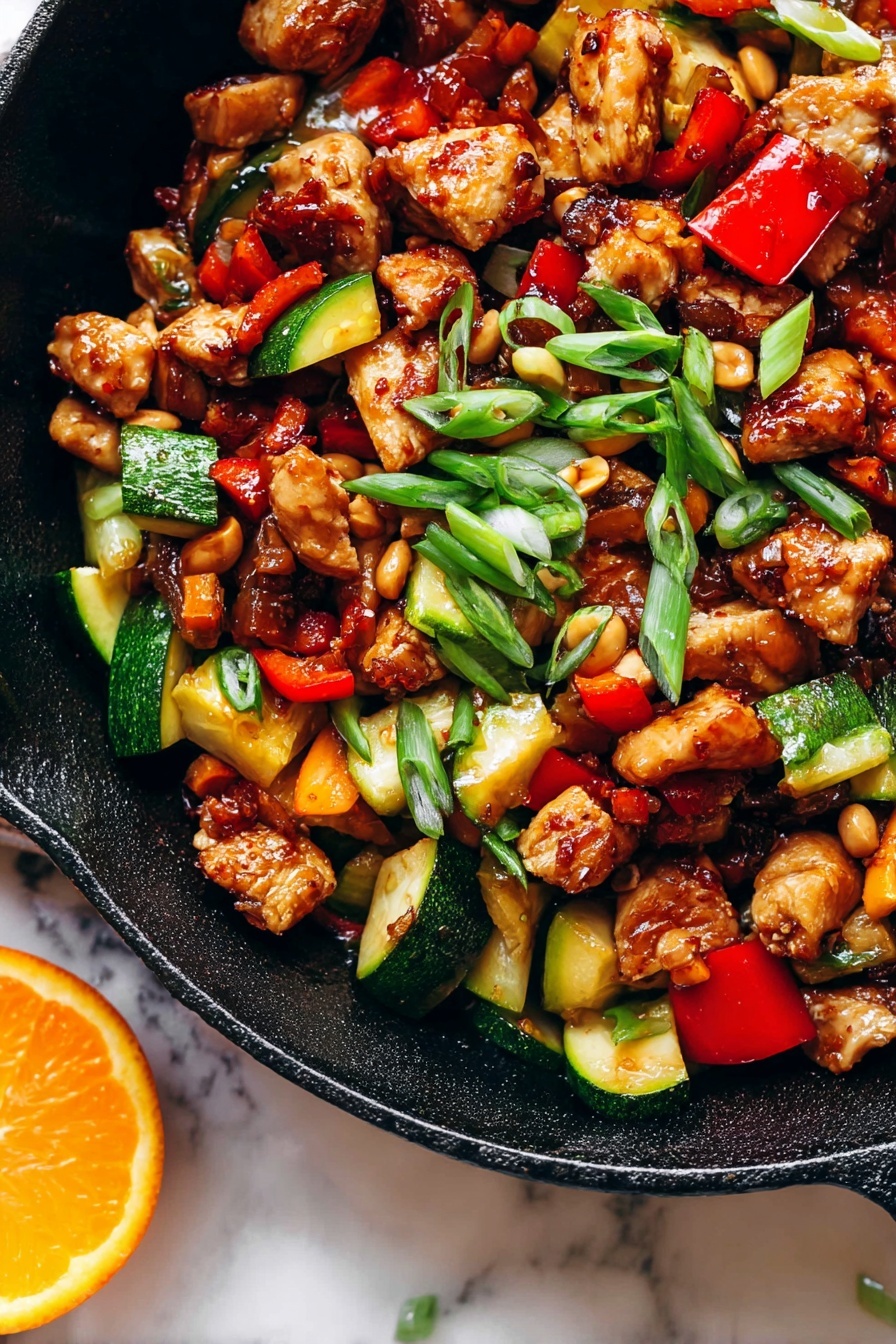 Kung Pao Chicken, Chinese stir-fry, spicy chicken recipe, easy weeknight dinner, Chinese takeout-inspired dishes - The image shows a close-up of a black cast iron pan filled with a colorful stir-fry dish that has three main layers. The first layer has browned chicken cubes with a shiny, caramelized texture scattered throughout the pan. The second layer has chopped vegetables, including bright red bell peppers and chunks of green zucchini with a cooked but firm look. The third layer is made up of small, light brown peanuts and thin slices of green onions sprinkled on top, adding a fresh touch. The pan sits on a white marbled surface, and there is a slice of bright orange on the edge of the pan. The light in the photo makes the food look vibrant and appetizing photo taken with an iphone --ar 2:3 --v 7