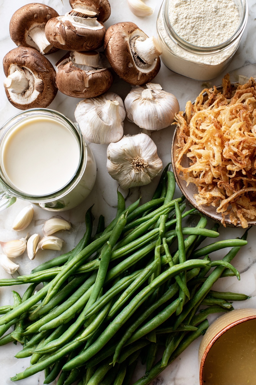 Vegan Green Bean Casserole, vegan holiday casserole, plant-based green bean dish, dairy-free green bean bake, vegan festive side dish - Flat lay of fresh green beans with vibrant deep green hues, a cluster of earthy brown sliced mushrooms showing their soft texture, several plump garlic cloves with smooth off-white skin, a small mound of golden crispy french fried onions with a crunchy look, a glass jug of creamy white coconut-almond creamer, a clear container of pale beige raw flour, and a small bowl of rich golden vegetable broth, all naturally arranged with some beans and garlic cloves gently overlapping, placed on white marbled surface, photo taken with an iphone --ar 2:3 --v 7