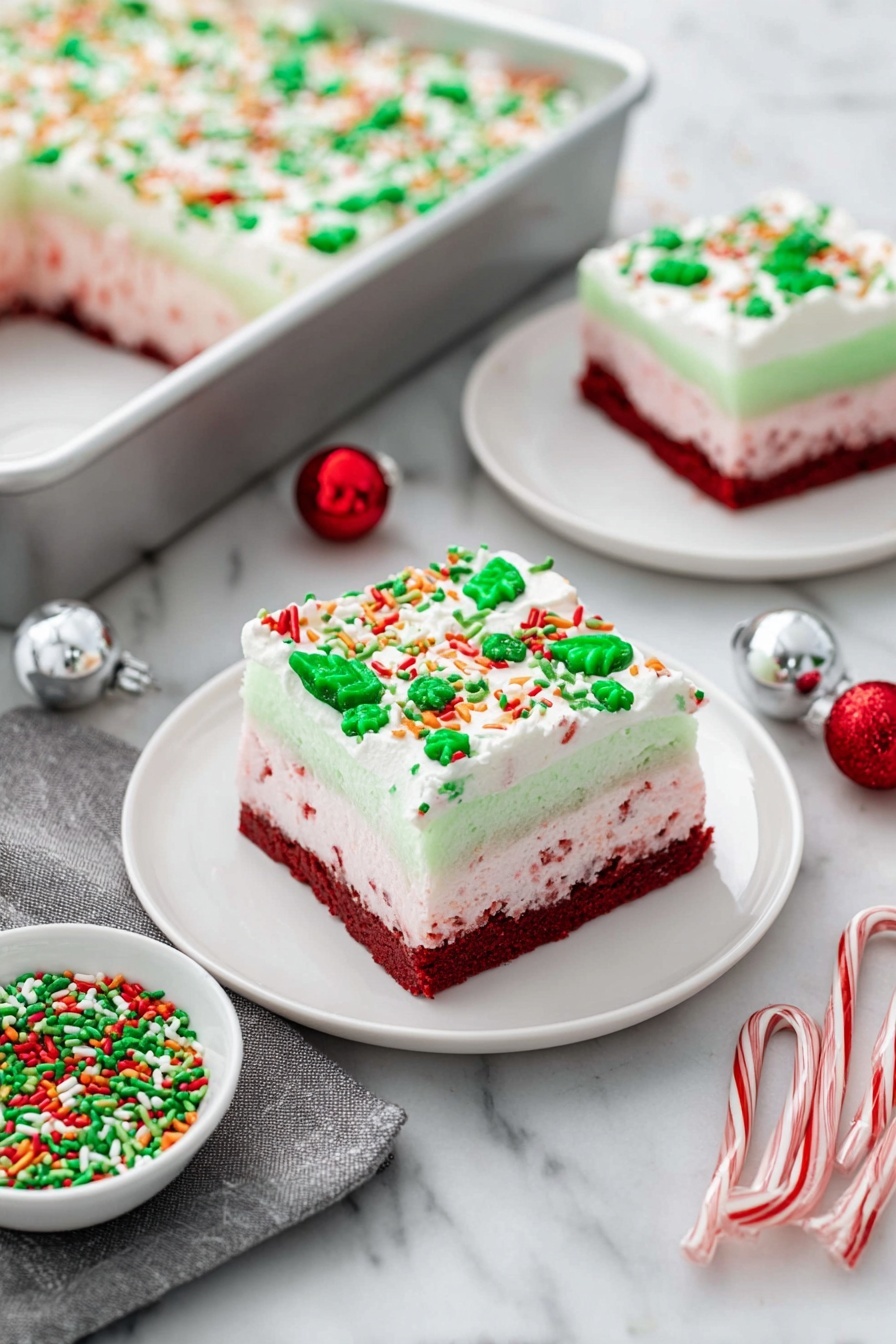 Christmas Red Velvet Lasagna Dessert, festive red velvet dessert, holiday layered dessert, Christmas lasagna recipes, colorful holiday desserts - The image shows a festive layered dessert square on a white plate, placed on a white marbled surface. The dessert has four distinct layers: the bottom layer is a dense dark red cake, followed by a light pink creamy layer with red specks, then a smooth pale green gelatin layer, and finally topped with a thick white whipped cream layer decorated with green, red, orange, and white sprinkles shaped like leaves, dots, and sticks. In the background, there is a silver baking pan with a large portion of the same dessert topped with sprinkles, and another smaller white plate holds a similarly decorated dessert square. Nearby, a small white bowl filled with matching festive green and red sprinkles sits next to two small candy canes, a silver ornament ball, a red ornament ball, and a gray cloth napkin. Photo taken with an iphone --ar 2:3 --v 7