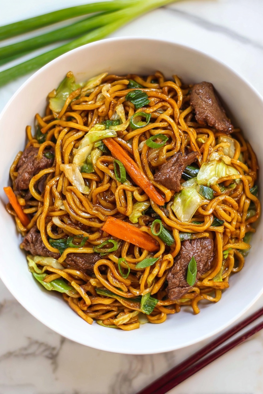 Easy Beef Lo Mein, beef noodle stir-fry, quick Asian dinner, savory beef recipes, family-friendly Chinese dishes - A white bowl filled with stir-fried noodles piled in the center with a shiny, dark orange color. Mixed throughout the noodles are pieces of cooked dark brown meat, bright orange carrot strips, light green cabbage leaves, and green onions with a fresh texture. The bowl sits on a white marbled surface, with green onions and dark red chopsticks placed nearby. The dish looks warm and saucy with a mix of soft vegetables and tender meat photo taken with an iphone --ar 2:3 --v 7