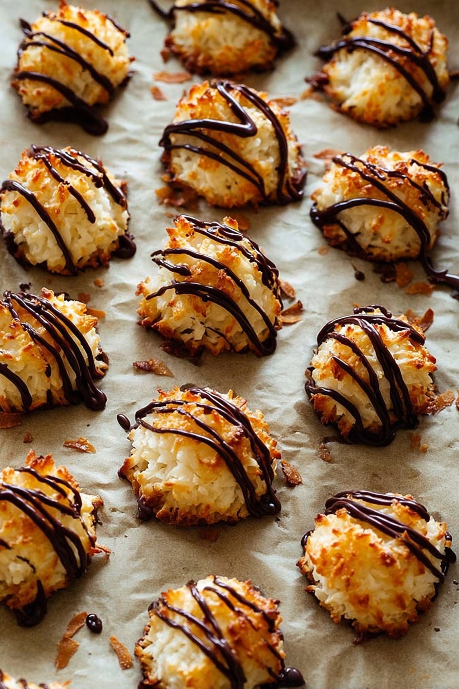 Chocolate Drizzled Coconut Macaroons, coconut macaroons with chocolate, easy coconut macaroon recipe, chewy coconut treats, chocolate-dipped coconut cookies - The image shows many small, round coconut macaroons with a golden-brown, slightly crispy texture on the outside and white inside. Each macaroon is topped with thin, shiny dark chocolate drizzle in irregular lines, adding a rich contrast in color and glossy texture. These treats are placed on a baking sheet lined with parchment paper that has a light brown color, and some small browned coconut flakes are scattered around. The background is a white marbled texture. photo taken with an iphone --ar 2:3 --v 7