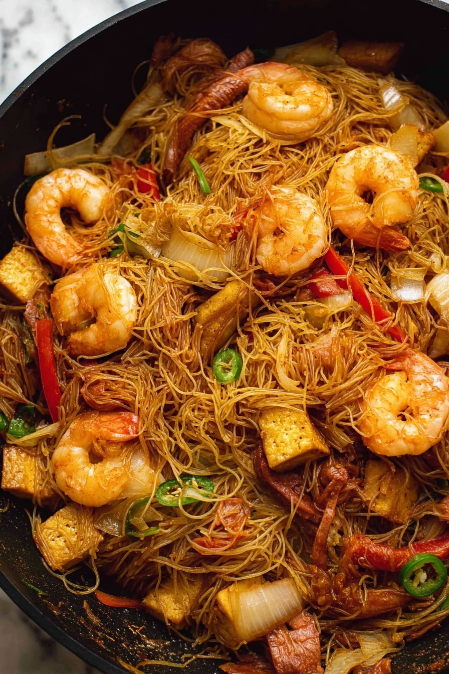 Singapore Noodles with Shrimp and Curry, quick Asian noodle dish, spicy shrimp stir-fry, easy curry noodle recipe, flavorful seafood noodle dish - A black pan filled with stir-fried thin noodles mixed with large cooked shrimp that are a light orange color with a slightly shiny texture. There are pieces of sliced red bell pepper and green chili scattered throughout the noodles, along with chunks of browned tofu that have a slightly crispy outside. Thin slices of cooked brown meat and translucent, soft-looking onion slices are also mixed in. The noodles are tangled and lightly coated in a soy-colored sauce. The background is a white marbled texture. photo taken with an iphone --ar 2:3 --v 7