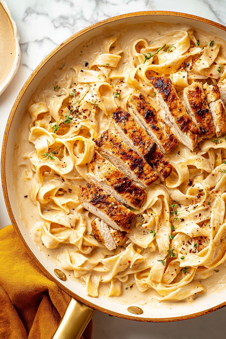 Creamy Fettuccine Alfredo with Chicken, chicken Alfredo pasta, easy chicken Alfredo recipe, restaurant-style Alfredo, weeknight pasta dinner - This image shows a white pan with a gold handle filled with wide flat noodles in a creamy light beige sauce, spread evenly across the pan as the bottom layer. On top, there are several thick pieces of grilled chicken, cut into strips with a browned, slightly charred crust and tender, light-colored inside. Small green herb bits and black pepper flakes are sprinkled over the noodles and chicken, adding texture and color contrast. The pan is placed on a white marbled surface, with a mustard yellow cloth partially visible on the lower left side. Photo taken with an iphone --ar 2:3 --v 7