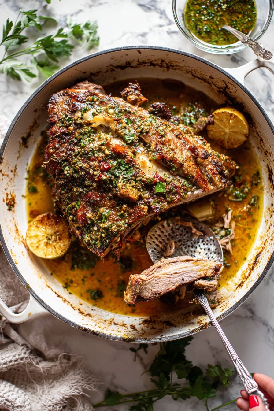 Slow Roasted Lamb Shoulder with Mint Sauce, Lamb shoulder recipe, slow roast lamb, mint sauce for lamb, tender lamb roast - A large piece of roasted meat with a brown crispy herb crust on top sits in the center of a white cast iron pot. The meat has visible bone, and the herb crust includes green parsley and spices giving a textured, uneven surface. Underneath the meat, there is a golden-brown juicy sauce with visible slices of lemon and pieces of cooked onions. A metal fork held by a woman's hand is pulling apart a slice of the tender meat, revealing its soft inner texture. To the right inside the pot is a hammered metal spoon resting in the sauce. Around the pot, there are scattered fresh green herbs on a white marbled surface, and a small glass bowl with herb sauce is placed behind the pot. photo taken with an iphone --ar 2:3 --v 7