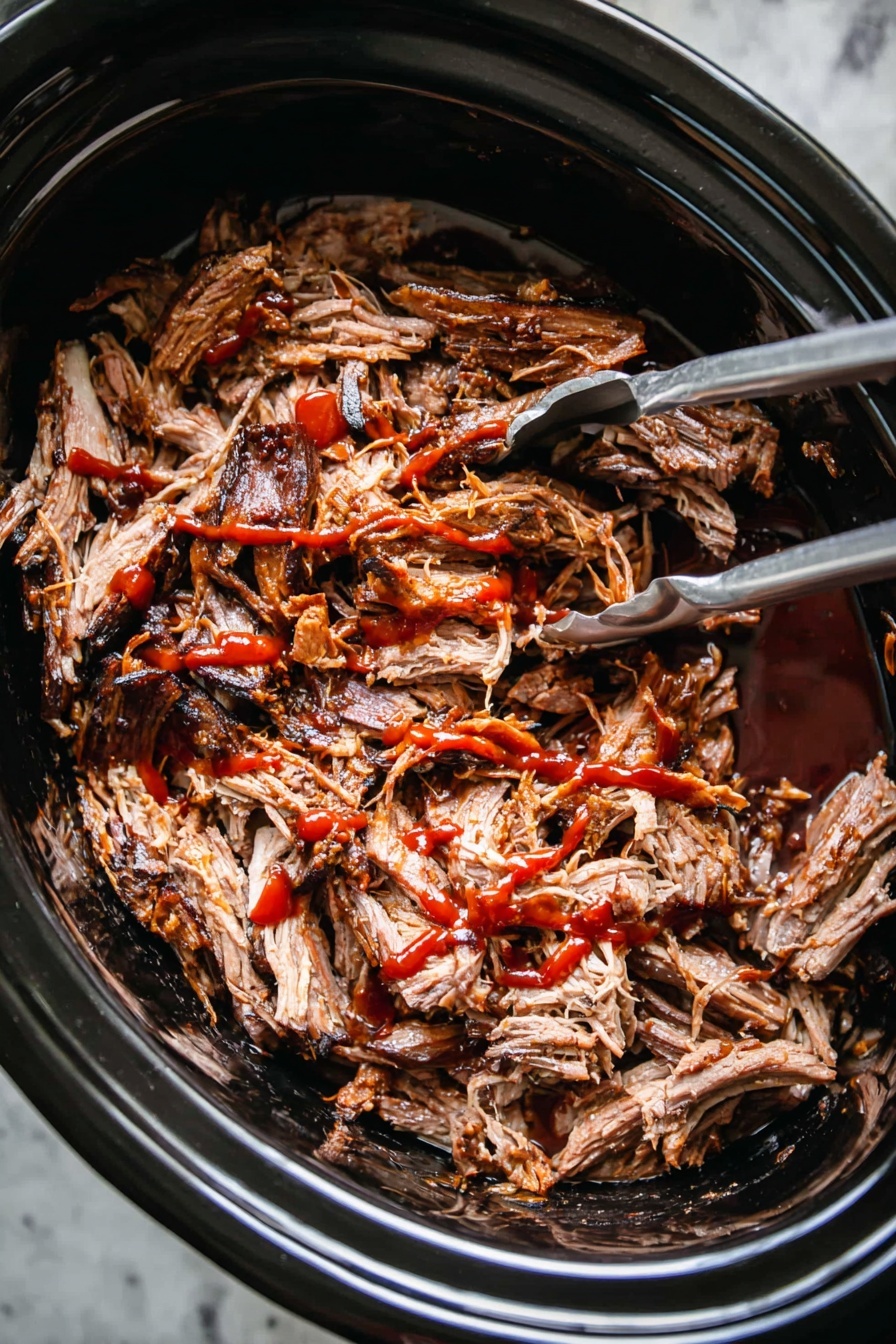 Slow Cooker Pulled Pork, tender pulled pork, easy slow cooker recipes, flavorful pork sandwiches, juicy pulled pork - A close-up image of shredded cooked meat with dark brown edges and lighter brown inside, placed inside a black slow cooker. The meat is covered with red sauce drizzled unevenly over the top. A silver fork and silver tongs are partially visible inside the slow cooker, placed on the left and right sides of the meat. The slow cooker sits on a white marbled surface. photo taken with an iphone --ar 2:3 --v 7