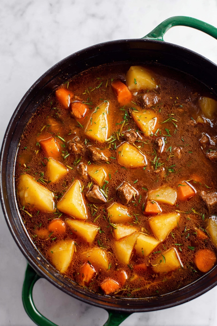 Vegan Irish Stew with Beer, Vegan Irish Stew, Plant-Based Irish Stew, Vegan Beer Stew, Irish Stew with Plant-Based Tips - A close-up top view of a large black pot with green handles filled with a rich brown stew. The stew has large chunks of yellow potatoes, orange carrot pieces, and small cubes of brown meat mixed evenly throughout. The broth is dark, slightly oily, with visible thin strands of herbs floating on the surface. The pot sits on a white marbled surface. photo taken with an iphone --ar 2:3 --v 7