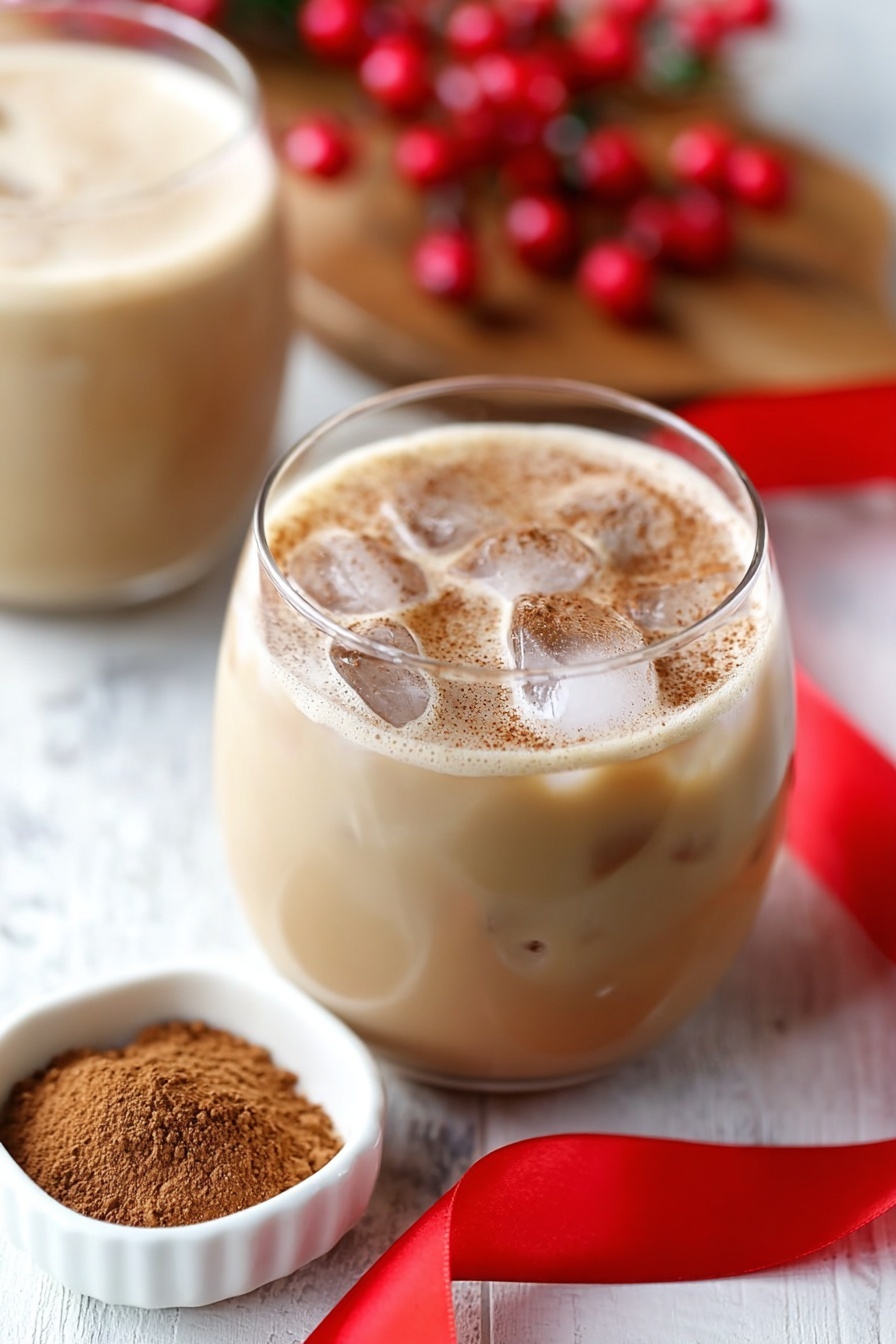 Eggnog White Russian Cocktail, festive eggnog cocktails, holiday White Russian, creamy winter cocktails, eggnog holiday drink - The image shows a clear glass filled with dark coffee at the bottom layer, with a woman's hand pouring white cream into it from above. The cream swirls into the coffee, creating a mix of light brown and creamy white patterns with a smooth texture. The glass sits on a wooden surface with a red ribbon nearby, and blurred bottles and red berries are in the background. photo taken with an iphone --ar 2:3 --v 7