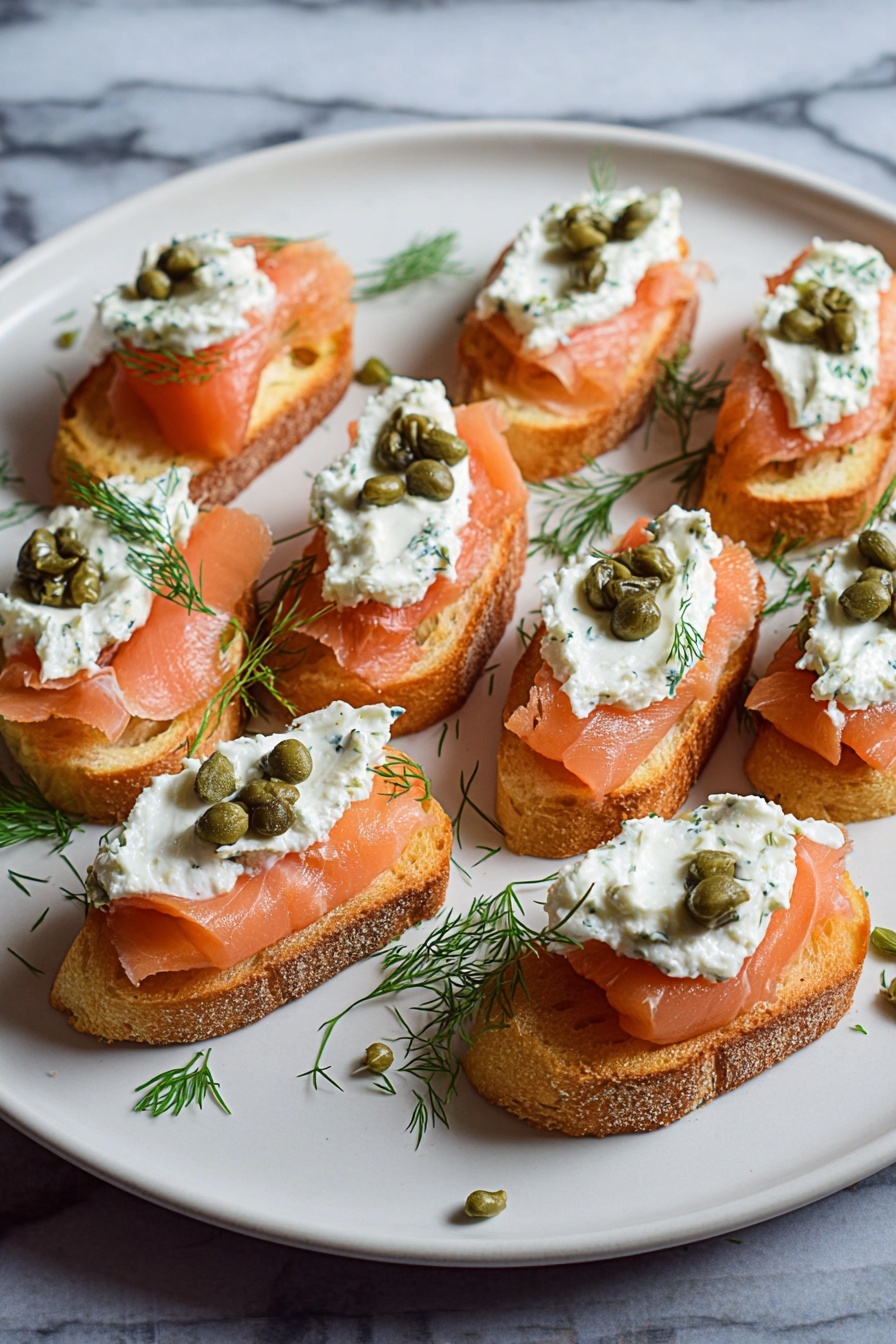 Smoked Salmon Crostini, smoked salmon appetizer, easy party appetizers, elegant canapés, seafood crostini - The image shows a white plate with several small toasted bread slices arranged in rows. Each slice is topped with three layers: the bottom layer is pinkish-orange smoked salmon with a smooth texture, the middle layer is a dollop of white creamy spread mixed with herbs, and the top layer features a few small green capers and a small sprig of fresh green dill. The plate sits on a white marbled surface with some scattered dill and capers around the edges. photo taken with an iphone --ar 2:3 --v 7