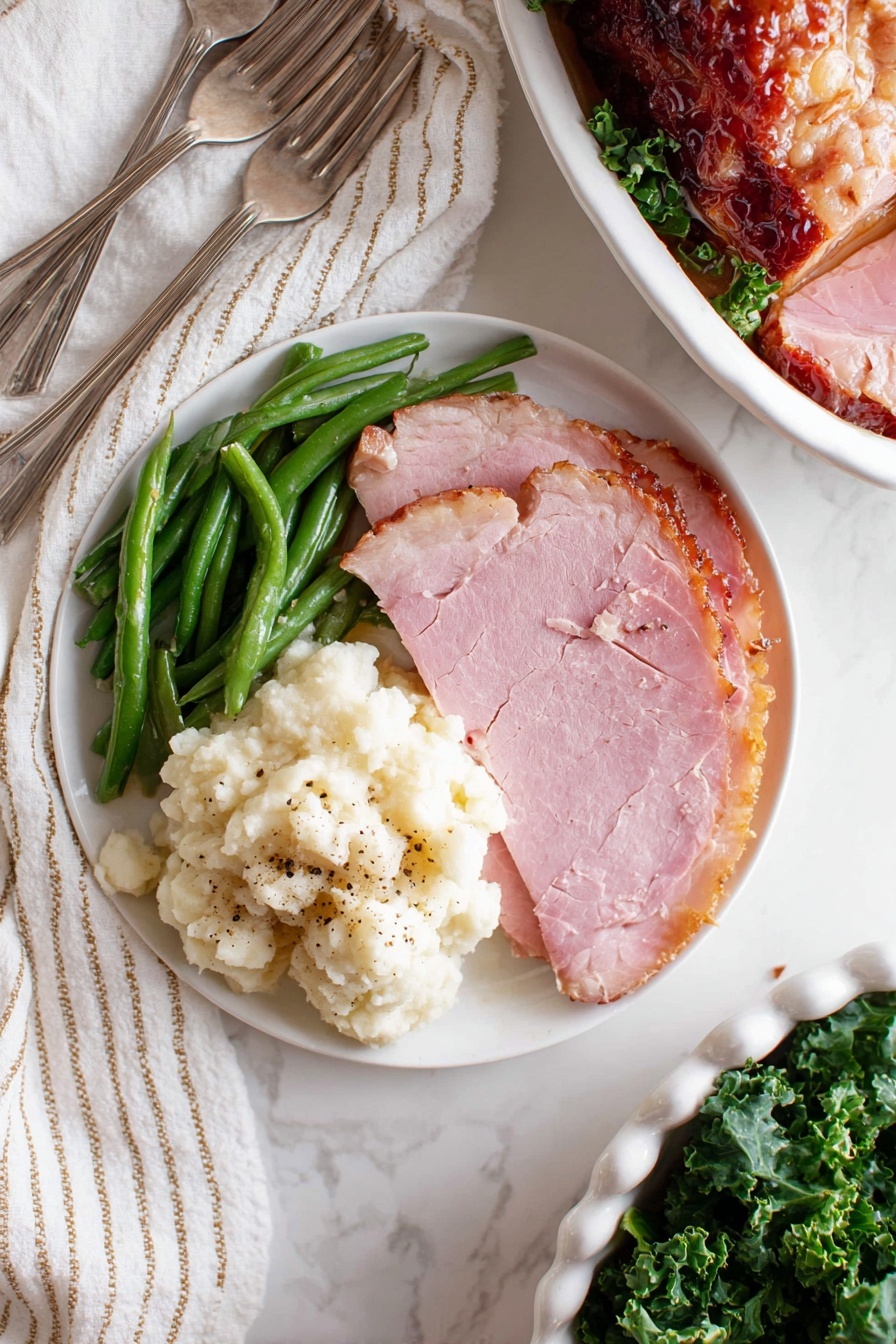 Baked Glazed Ham, glazed ham recipe, holiday ham, easy ham dinner, sweet and tangy ham - A white round plate shows a simple meal with three parts: green beans on the top left, fluffy mashed potatoes with some black pepper on the bottom left, and two thick slices of pink ham on the right, with a light brown edge. The plate sits on a white marbled surface with a white and beige striped cloth on the top left and two silver forks below the plate. On the right top corner, there is a partial view of another white round plate with a slice of ham and green beans. In the bottom right, a white dish filled with sliced glazed ham resting on green leafy kale is partially shown. photo taken with an iphone --ar 2:3 --v 7