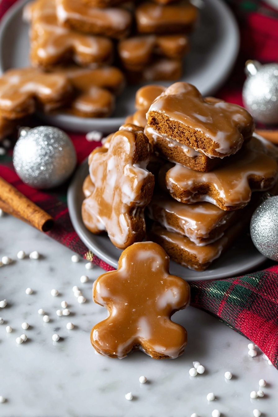 Chewy Gingerbread Man Cookies, gingerbread cookies with chewy texture, holiday gingerbread treats, easy gingerbread man recipe, soft gingerbread cookies - A stack of seven rectangular gingerbread cookies covered in a shiny light brown icing is placed on a white marbled surface. On top, one cookie is broken in half to show the soft, slightly crumbly inside, which is a warm orange-brown color. The glaze has a smooth texture with a few small spots where it drips a little around the edges. The cookies are stacked unevenly, giving a casual, fresh-baked look with more cookies softly blurred in the background. photo taken with an iphone --ar 2:3 --v 7