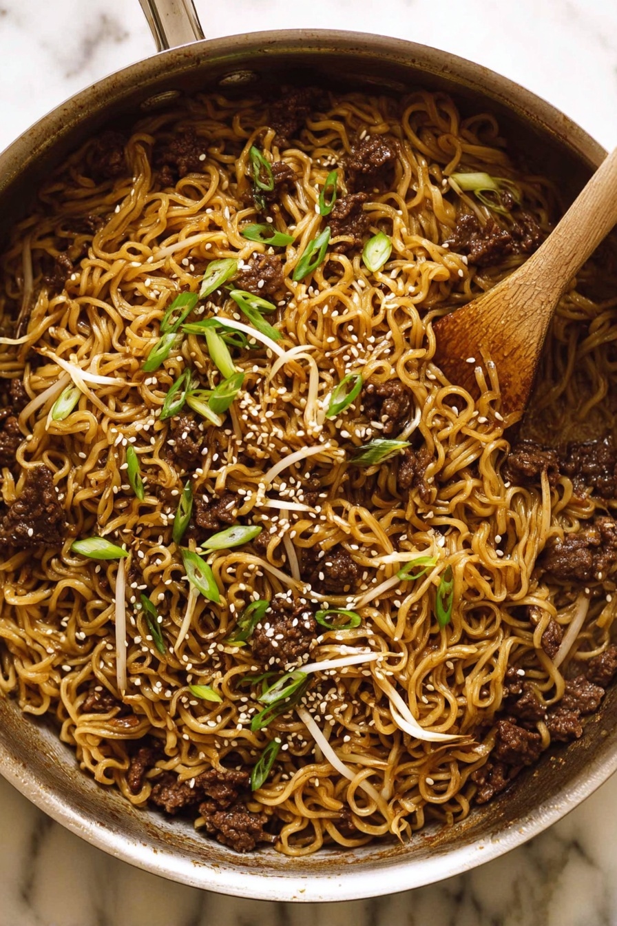 Quick Asian Beef Ramen Noodles, Asian beef ramen recipe, easy beef ramen, speedy ramen dinner, flavorful beef noodle bowl - The image shows a metal pan filled with cooked noodles mixed with small pieces of dark brown meat and light bean sprouts. The noodles have a slightly shiny, brown color from the sauce. On top, there are sliced green onions and white sesame seeds scattered, adding texture and color contrast. A wooden spoon rests inside the pan, partially covered by the food. The pan sits on a white marbled surface. photo taken with an iphone --ar 2:3 --v 7