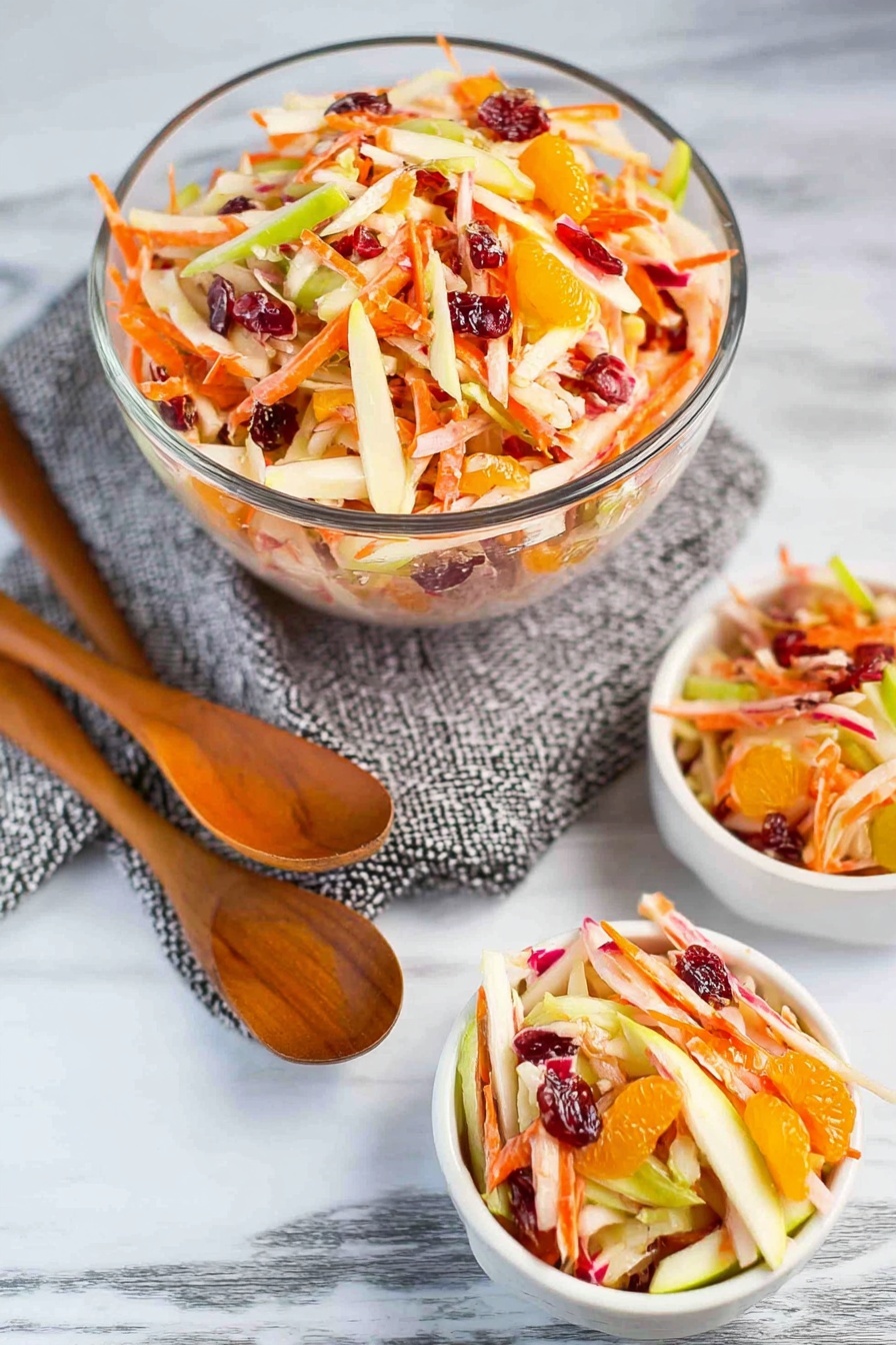 Carrot Apple Salad with Cranberries and Mandarin, healthy fruit salad with cranberries and mandarins, easy colorful vegetable salad, fresh apple and carrot side dish, quick fruit salad recipe - A wooden spoon holds a colorful mix of salad with several layers: thin, long orange carrot strips, off-white apple slices, small bright orange mandarin pieces, and shiny dark red dried cranberries, all coated in a creamy dressing. Below, a clear glass bowl is filled with the same mix, showing a dense, fresh, and juicy texture with different colors like green apple skin peeking through. The background is a white marbled surface. photo taken with an iphone --ar 2:3 --v 7
