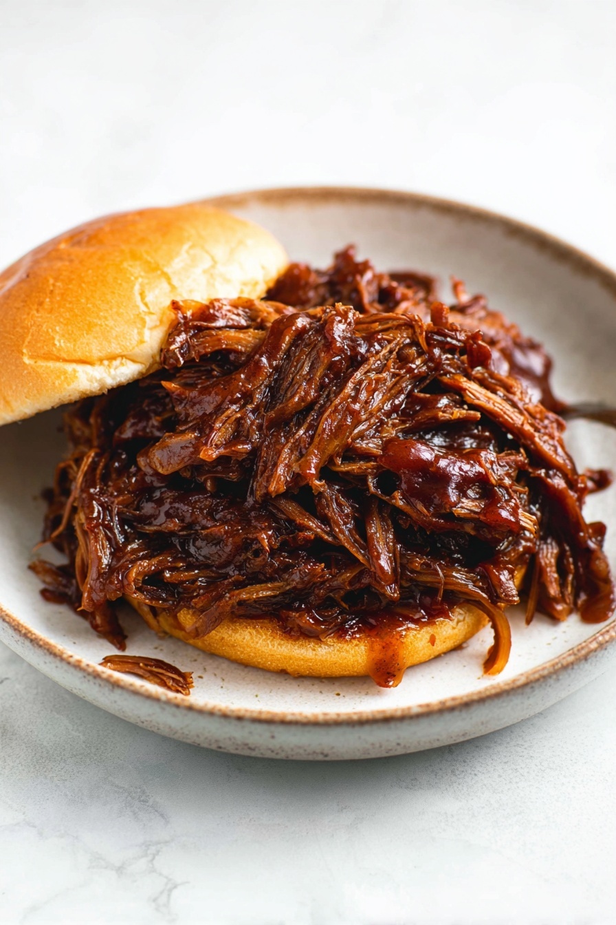 Slow Cooker Honey BBQ Beef Brisket, slow cooker beef brisket with honey bbq, tender beef brisket recipes, easy slow cooker beef dinner, smoky sweet BBQ brisket - A sandwich on a soft, shiny light brown bun with two layers: the bottom bun and the top bun. Between them is a large pile of dark brown shredded meat covered in thick, shiny barbecue sauce that drips slightly onto the white marbled surface and around the sandwich. The sandwich sits on a white plate with a soft black color and a slightly glossy texture, and the background is a white marbled texture. photo taken with an iphone --ar 2:3 --v 7