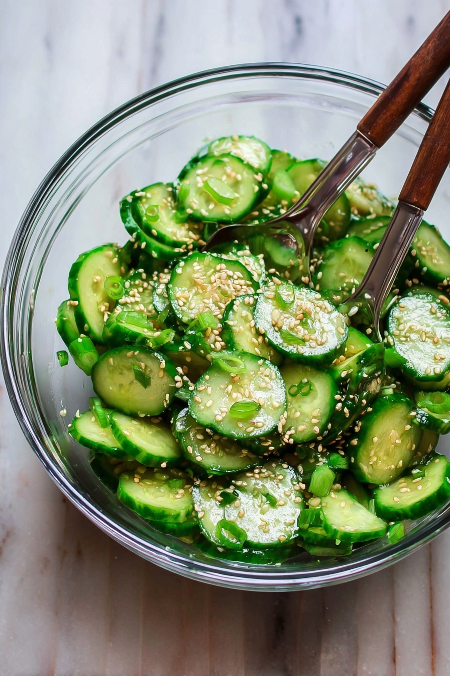 Asian Cucumber Salad, cucumber salad recipe, Asian side dish, crunchy cucumber salad, quick healthy salad - A clear glass bowl filled with sliced green cucumbers mixed with small pieces of green onions and sprinkled with light brown sesame seeds, two wooden salad forks with metal handles rest inside the bowl touching the cucumbers, all placed on a white marbled surface photo taken with an iphone --ar 2:3 --v 7