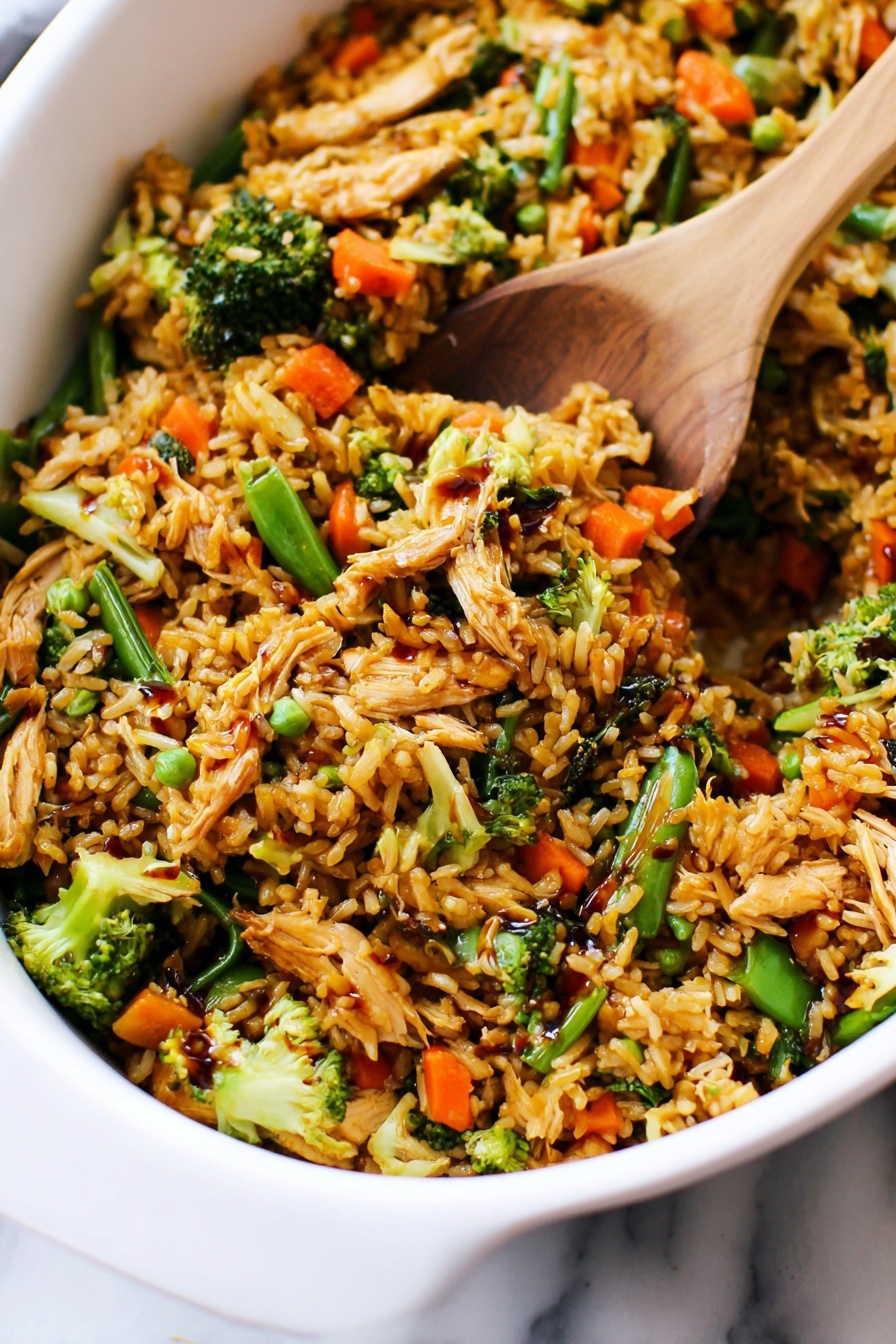 Easy Teriyaki Chicken Casserole, Teriyaki Chicken Bake, Healthy Chicken Casserole, Simple Chicken Dinner, Weeknight Chicken Recipes - The image shows a close-up of a white dish filled with a colorful fried rice mix. The dish has multiple layers: the base layer is golden-brown cooked rice, mixed with small pieces of shredded light brown cooked chicken. Scattered throughout are bright green broccoli florets and snap peas, as well as vibrant orange baby carrots. The vegetables add texture and color contrast, while some parts of the rice have a glossy look from a dark soy sauce drizzled on top. A wooden spatula is partially buried in the mixture, lifting some of the rice and vegetables. The dish is placed on a white marbled surface. Photo taken with an iphone --ar 2:3 --v 7